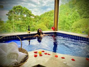 a woman in a swimming pool with a bottle of wine at Chales Cabana Garden in Monte Verde