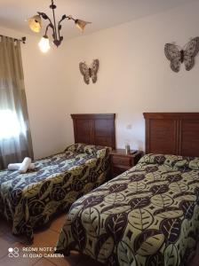 2 camas en una habitación de hotel con mariposas en la pared en Hostal el Hayedo, en Cantalojas