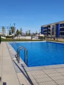 a swimming pool with blue water in front of a building at Apartamento nuevo, accesible y con piscina !!! in Salamanca