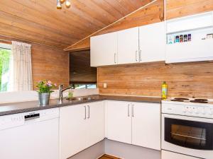 Three-Bedroom Holiday home in Knebel 22 في Skødshoved Strand: مطبخ بدولاب بيضاء وسقف خشبي