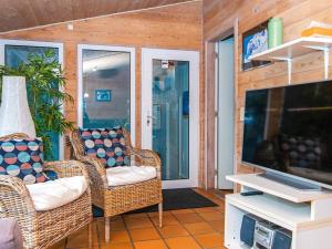 een veranda met rieten stoelen en een flatscreen-tv bij Three-Bedroom Holiday home in Knebel 22 in Skødshoved Strand