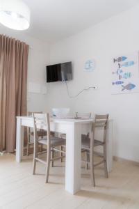 mesa blanca con sillas y TV en la pared en La Terrazza sul Mare, en Marzamemi
