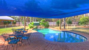 a blue umbrella over a pool with tables and chairs at Mulga Country Motor Inn in Charleville