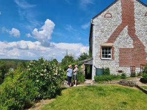 dos personas parados fuera de una casa de piedra en Maison de campagne avec superbe vue panoramique!, en Bousignies-sur-Roc