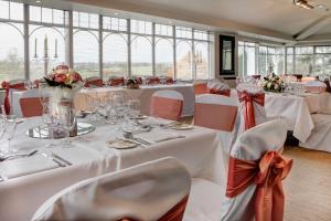 a banquet room with white tables and chairs with flowers at Windmill Village Hotel, Golf Club & Spa, BW Signature Collection in Coventry