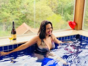 a woman in a hot tub with a bottle of wine at Chales Cabana Garden in Monte Verde