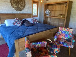 a bedroom with a bed and two chairs at Chales Cabana Garden in Monte Verde