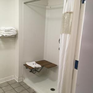 a bathroom with a shower with a wooden table at President Inn & Suites in Gettysburg