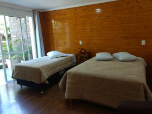 2 camas en una habitación con pared de madera en Casa Zanata, en Gramado