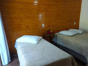 a room with two beds and a wooden wall at Casa Zanata in Gramado