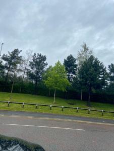 a road with a fence next to a field with trees at CityMan Manchester in Manchester
