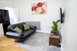 a living room with a black leather couch and a table at CityMan Manchester in Manchester
