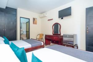 a bedroom with two beds and a desk and a tv at Ayenda 1309 Villa Dilia in Barranquilla