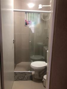 een badkamer met een toilet en een glazen douche bij Apartamento aconchegante in Ubatuba