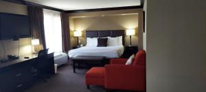 Habitación de hotel con cama y silla roja en Parkwood Inn & Suites en Manhattan