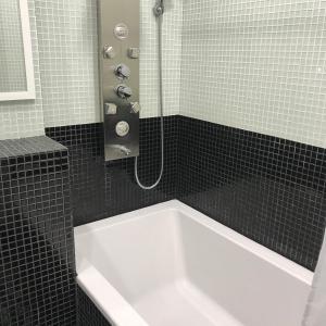 a white bath tub in a black tiled bathroom at Airport apartment in Saint Petersburg
