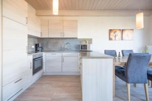ダゲビュルにあるFerienhaus Nordspitzeの白いキャビネット、テーブルと椅子付きのキッチンが備わります。