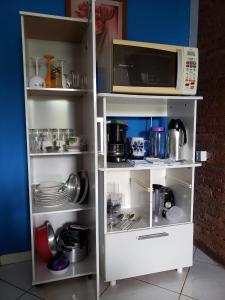 um armário branco com pratos e um micro-ondas em Casa Star em Monte Sião