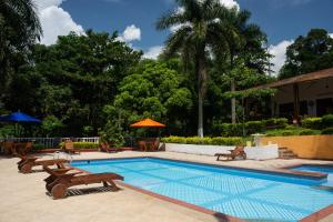 a swimming pool with benches and chairs next to a resort at Ikara Hotel Campestre Villeta in Villeta