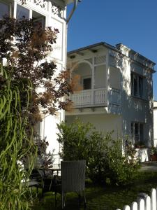 ein weißes Gebäude mit einem Balkon und einem Stuhl in der Unterkunft Apartment Gartenstrasse 3 in Ostseebad Sellin