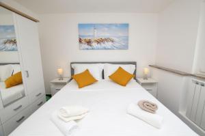 a bedroom with a white bed with yellow pillows at Apartments Villa Sofia in Martinšćica