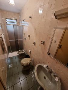 La salle de bains est pourvue d'un lavabo, de toilettes et d'une douche. dans l'établissement Hotel Colonial, à São João del Rei