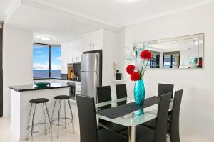 uma cozinha e sala de jantar com uma mesa de vidro e cadeiras em Cairns Luxury Waterfront Apartment em Cairns
