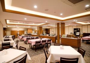 um restaurante com mesas e cadeiras brancas e um buffet em Grand Hotel Fujika em Nayoro