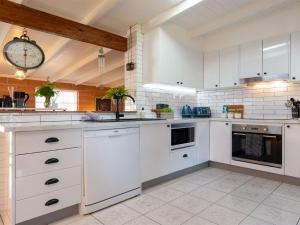 a kitchen with white cabinets and a clock on the wall at Cudgee in Currarong