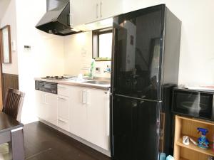 a kitchen with a black refrigerator and a sink at るり渓清流台Z-5-6号棟 in Habu