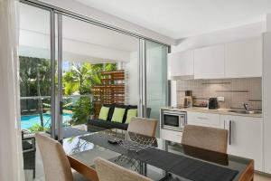 a kitchen and dining room with a table and chairs at Palm Cove Beach Apartment in Palm Cove