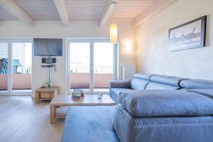 uma sala de estar com um sofá azul e uma mesa em Ferienhaus Nordspitze em Dagebüll