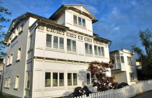 a white building with a white fence in front of it at Apartment Gartenstrasse 3 in Ostseebad Sellin