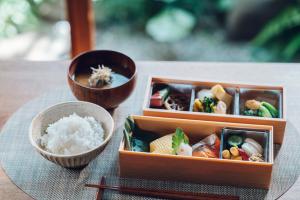 two boxes of food and a bowl of rice on a table at Asahi House Kyoto Dog Friendly in Kyoto