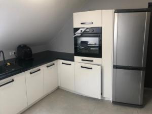 kuchnia z białymi szafkami i lodówką w obiekcie Klimatyzowane Apartamenty i Pokoje przy Targach Kielce w Kielcach
