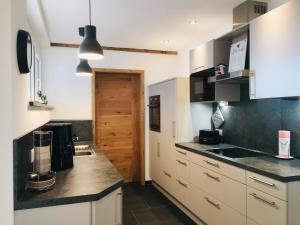 a kitchen with white cabinets and a black counter top at Ferienscheune Maria in Lichtenfels