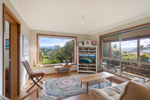 a living room with a couch and a large window at Monaro Cottage in Eden