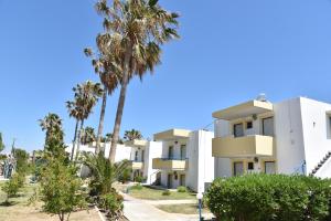 a building with palm trees in front of it at 1-Bedroom Kos Olympia Apartment at Lambi Beach in Lampi