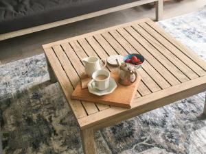 a wooden coffee table with two mugs and a tray at Beachfront 4 Unit 4 of 12 Bundella Ave LC in Lake Cathie