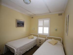 two twin beds in a room with a window at Beachfront 4 Unit 4 of 12 Bundella Ave LC in Lake Cathie