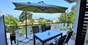 a patio with a table and an umbrella on a balcony at Apartments Martina in Njivice