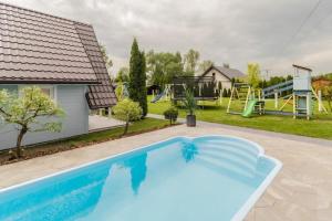 una piscina en un patio con parque infantil en Puszczykowo, en Stegna