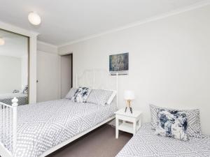 Un dormitorio blanco con dos camas y un espejo. en Sundowner Apartment 5, en The Entrance