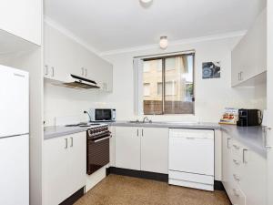 a white kitchen with white cabinets and a window at Sundowner Apartment 5 in The Entrance