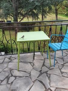 een vogel op een tafel naast een blauwe stoel bij Le Curieux de Conques in Saint-Cyprien-sur-Dourdou