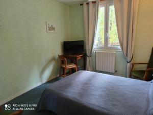 een slaapkamer met een bed, een bureau en een televisie bij Hôtel Auberge de La Nauze in Sagelat