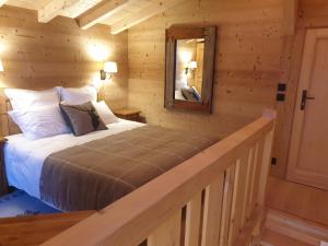 um quarto com uma cama num chalé de madeira em BARMADZA Mazots de Charme em Demi-Quartier