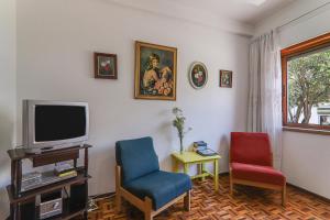 a living room with two chairs and a tv at Casa Tangerina in Tavira