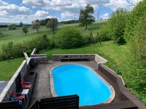 een zwembad met een terras en stoelen eromheen bij Spacious old farmhouse with top-of-the valley view in Trois-Ponts