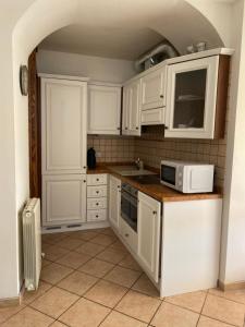 cocina con armarios blancos y microondas en AGORA' Home, en Gardone Riviera